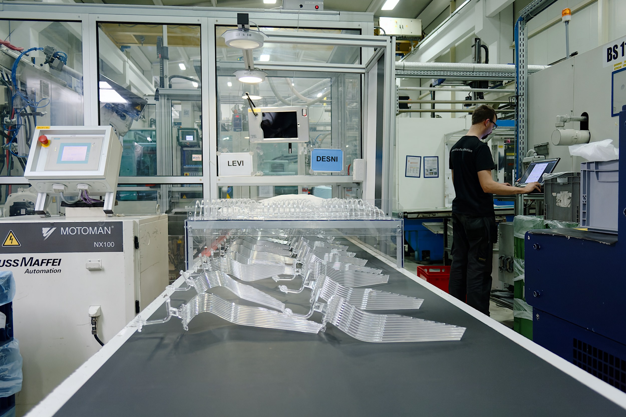 Transparentni izdelki iz plastike za avtomobilske luči in delavec, ki pripravlja stroj